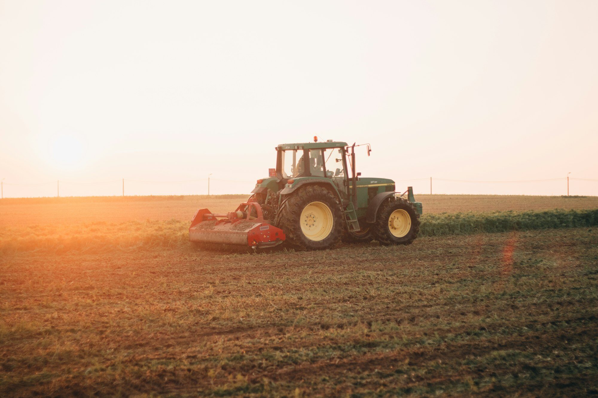 Green tractor working a field at golden hour