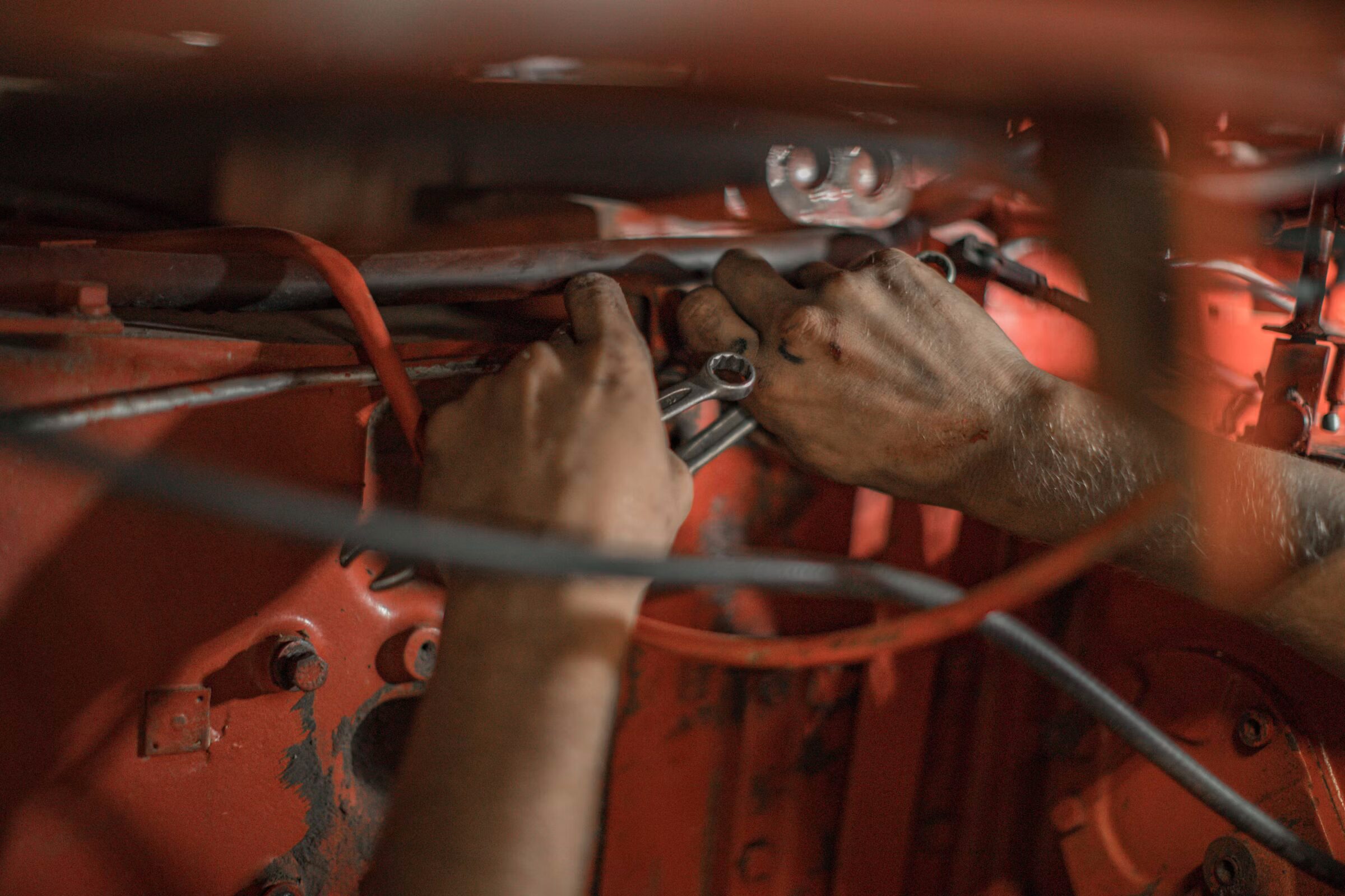 Mechanic’s hands wrenching inside an orange machine frame
